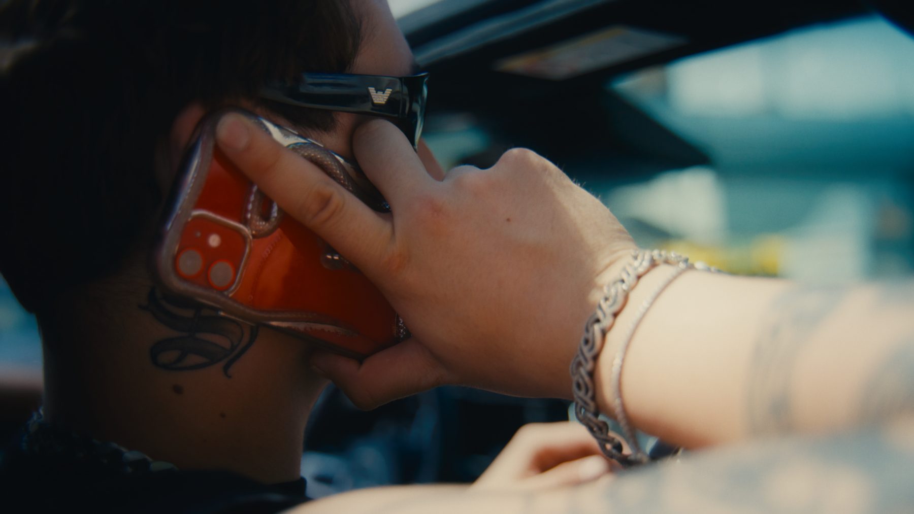 Close frame of an artist on the phone in the car, shot from behind