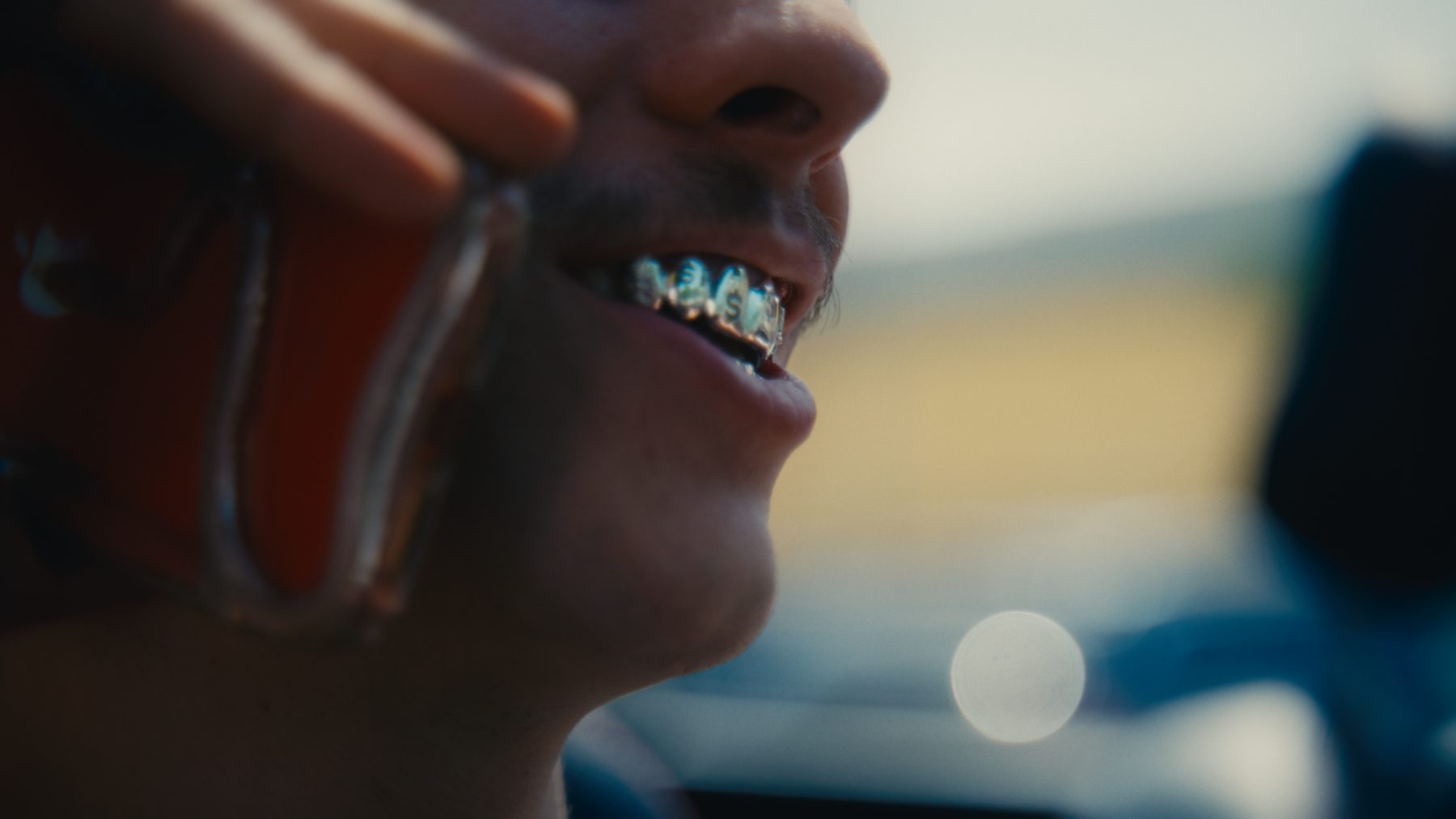 Macro frame of his grill as he takes a call, phone up against his cheek