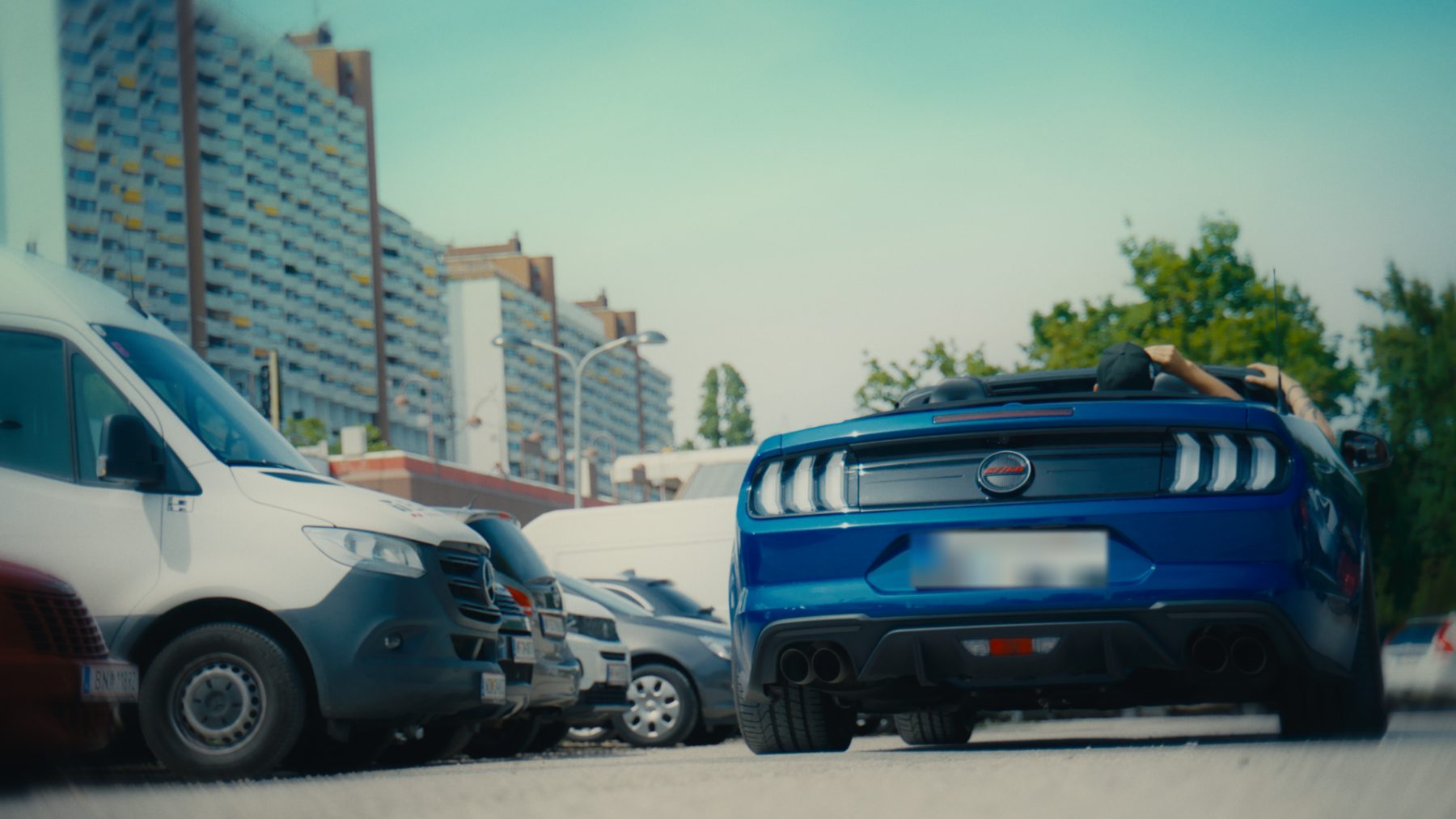 Blue Mustang convertible parked in front of the Vienna tower blocks