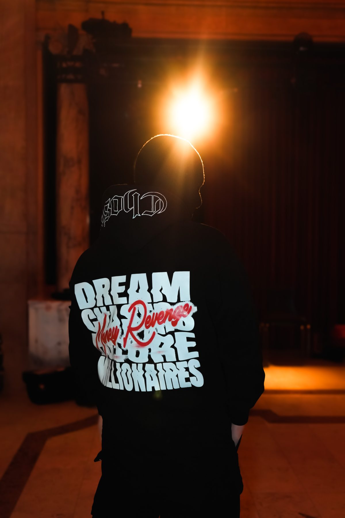 Back of the Dream Chasers hoodie print, backlit by a single lamp