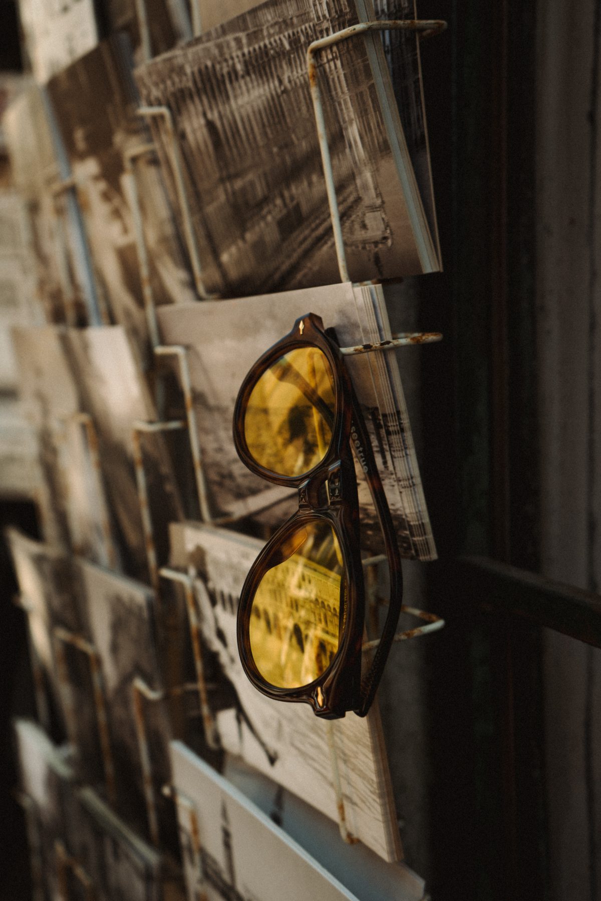 Tortoise frame with yellow lenses hooked on a postcard rack