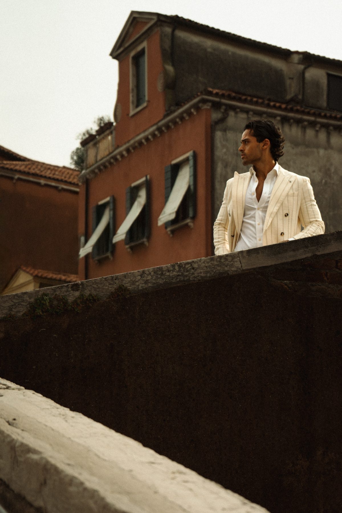 Model on a bridge wall against the Venice rooftops