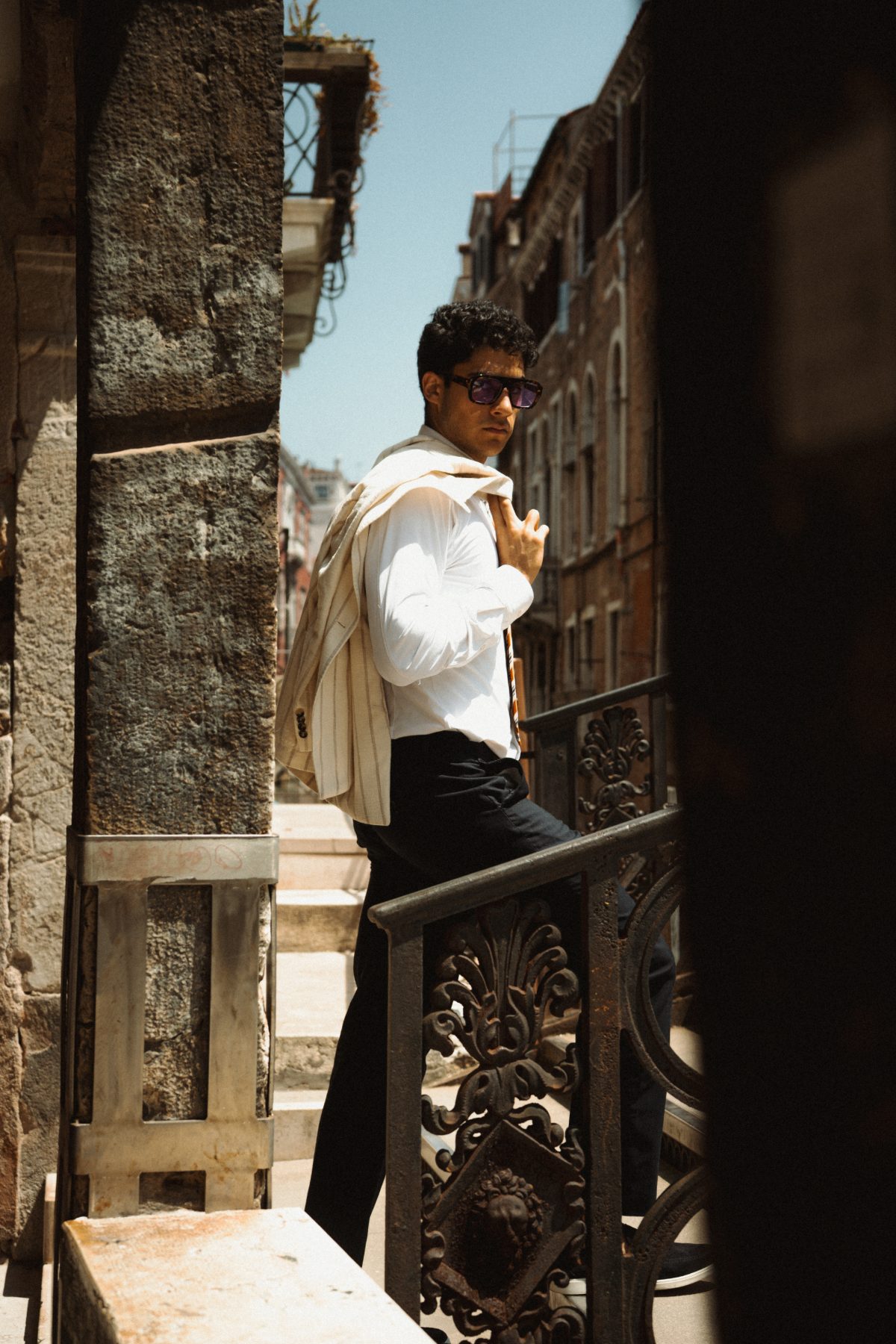 Model with his jacket over one shoulder at an iron railing